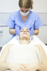 Beautiful woman at spa salon, Cosmetician woman applying facial mask.