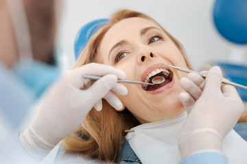 Scrupulous competent dentist cleaning patients teeth