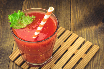 smoothie glass from tomatoes with straws on a wooden background/glass of tomato juice with straws...