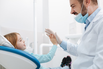 Obraz premium Cheerful great dentist giving his little patient a high five
