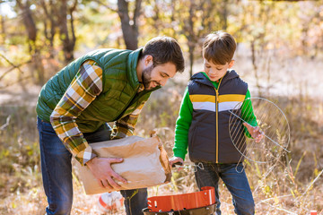 Father and son putting coals in grill