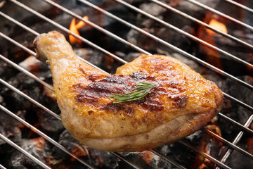 Grilled chicken leg over flames on a barbecue