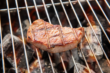 Grilled pork steaks over flames on the grill