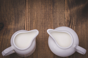 two white creamer on a wooden background. Top view/two white creamer on a wooden background