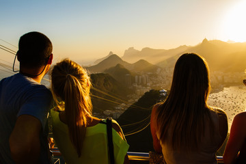 Tourists watching from the Sugarloaf mountain over Rio to Corcovado on a beautiful evening - obrazy, fototapety, plakaty