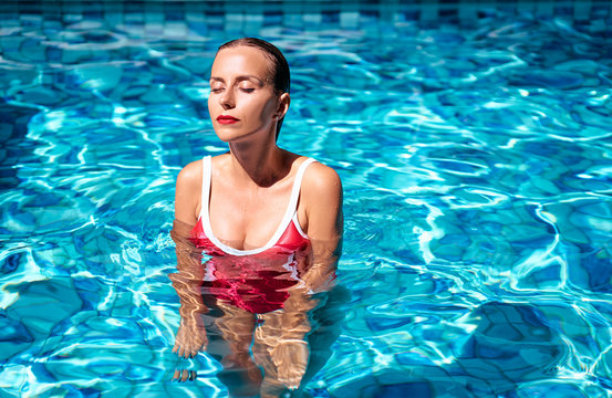 Summer vacation and relaxation. Beautiful young woman in red swimsuit at swimming pool.
