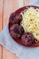 Cutlets with spaghetti in a rustic style. Beef mitbols with pasta on a clay plate.