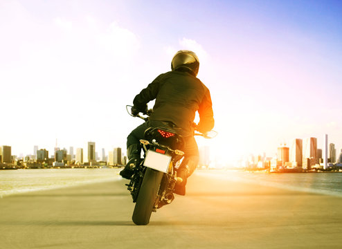 Fototapeta rear view of man riding motorcycle on urban traffic road for people leisure traveling theme