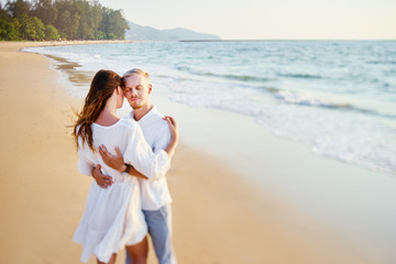 Romantic vacation. Love and tenderness. Young loving couple embracing on the sea sand beach.