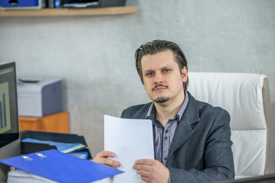 A young businessman is giving a serious expression. He is dealing with paper work.