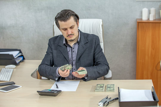 A young businessman is being serious when he is counting the American dollars in his hands.
