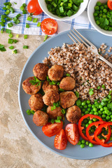 Buckwheat with meatballs and vegetables on a concrete background. Lunch for the whole family.