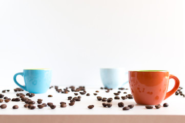 Colorful coffee cups on white table with beans