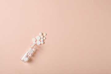 White pills spilling out of a toppled transparent glass pill bottle