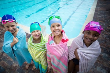 Little swimmers wrapped in towels standing at poolside - Powered by Adobe