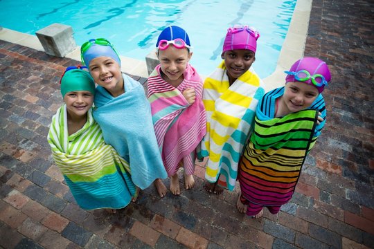 Swimmers wrapped in towels standing at poolside