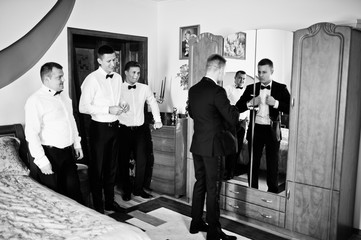 Fototapeta na wymiar Groom wears on his room at morning wedding with best mans.