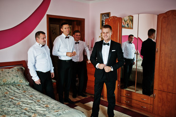 Groom wears on his room at morning wedding with best mans.