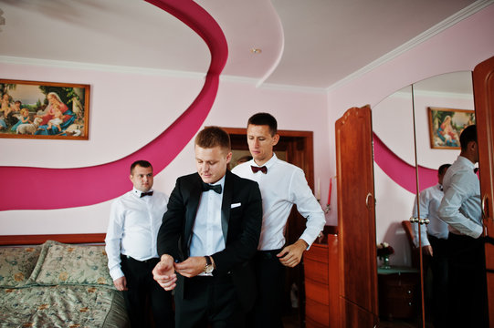 Groom wears on his room at morning wedding with best mans.