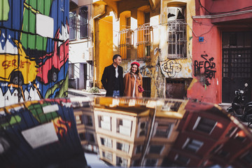 Happy couple walking at street with colorful painted walls with graffiti