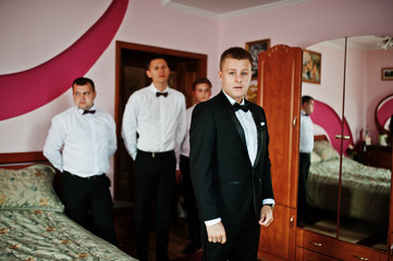 Groom wears on his room at morning wedding with best mans.