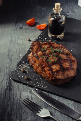 Pork steak with tomatoes and sauce on the slate Board side view