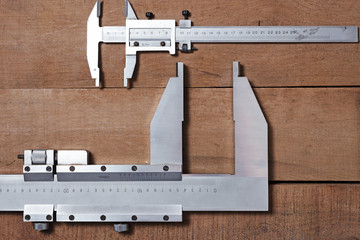 Carpenter tools on the wood table background. Big and small Vernier caliper 