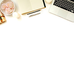 Minimalistic feminine work place. White office desk table with laptop, roses, vintage white tray, notebook, candles, pen and pencil. Top view with copy space, flat lay