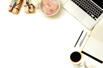 Stylish feminine work place. White office desk table with laptop, roses, vintage white tray, notebook, coffee cup, pen and pencil. Top view with copy space, flat lay