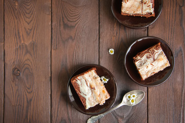 Brownie cheesecake squares in a brown small plates on a wooden background. Close up and top view.