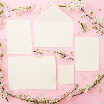 Spring flowers and calligraphy cards on pink background. Flat lay, top view.