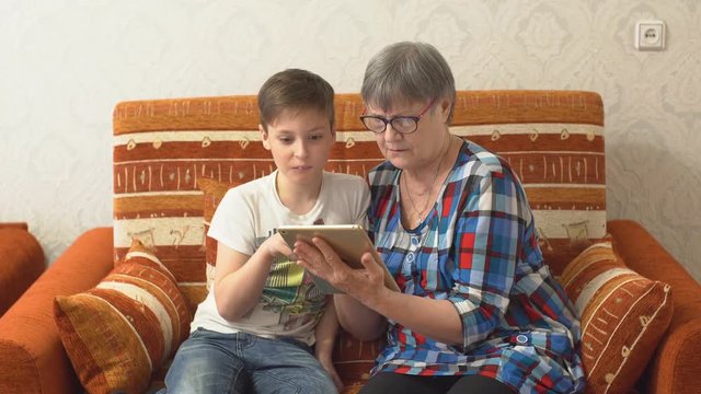 Grandson teaches grandmother to play in a tablet