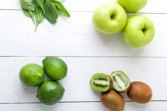 Ingredients for smoothie. Green fruits on white wooden background. Apple, lime, spinach, kiwi. Detox. Healthy food. Top view.
