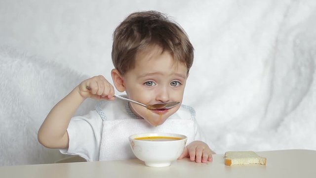 Boy child eating soup with a spoon
