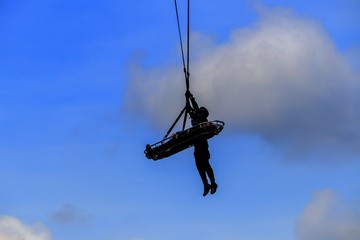 Fototapeta na wymiar silhouette Soldier rescue emergency by army helicopter with rope on blue sky