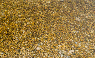 Lake pebbles,Italy,Trentino,Lake Levico,1 April 2017, abstract background of lake pebbles,yellowish shade, the water surface is transparent