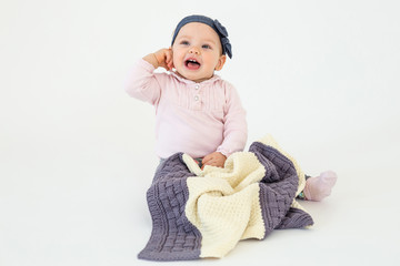 Cheerful girl sitting on floor with plaid