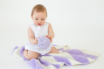 Little baby girl playing with threads ball.