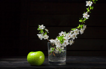 Green apples with blossoms on wooden table
