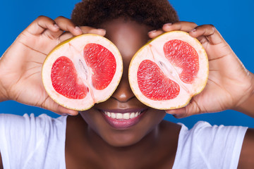 African-American woman with grapefruit on blue background, close
