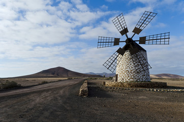 Eine alte restaurierte Windmühle in kahler Landschaft.
