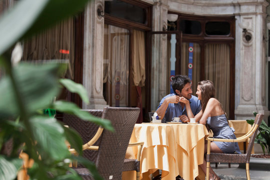 Young couple sitting outside cafe, Turin, Piedmont, Italy