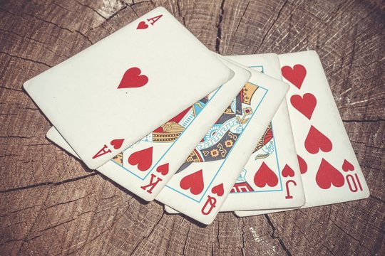 Playing cards on wooden surface. Royal flush.