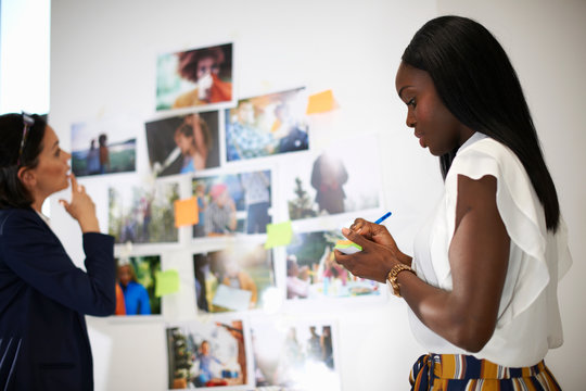 Colleagues in office discussing photographs on wall