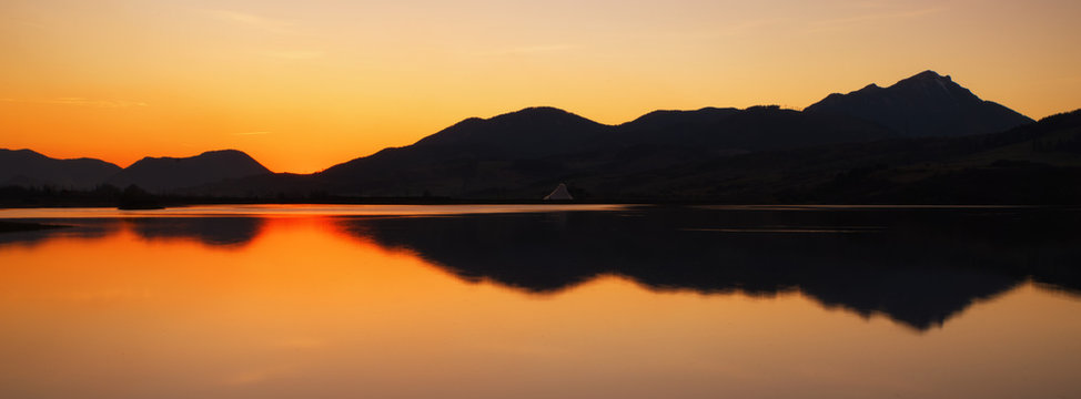 Fototapeta Colorful sunset over lake and mountains
