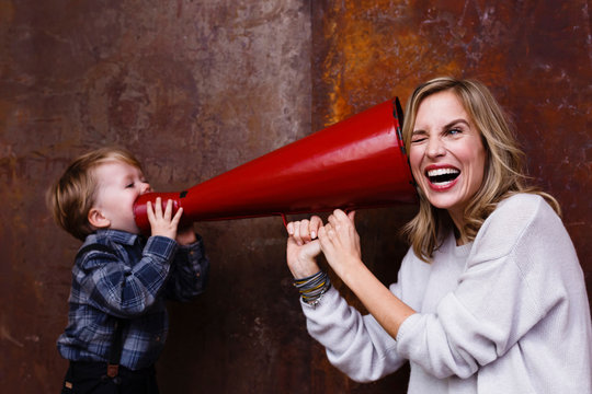 Young boy speaking into megaphone, woman holding megaphone to her ear