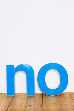 Large three-dimensional letters on wooden floor spelling the word NO