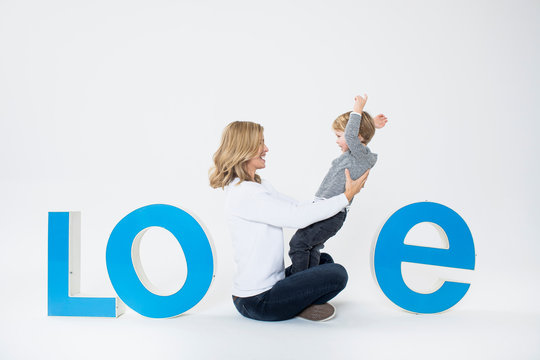 Mother and son sitting between three-dimensional letters, creating the word LOVE