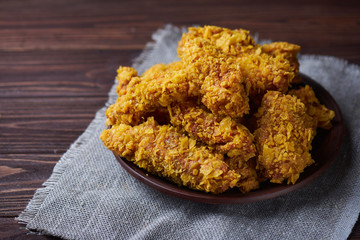 Crispy fried chicken breast on an old rustic wooden background with a sackcloth napkin, Close-up. With a lot of copy space.