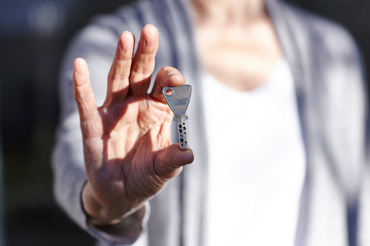 Senior woman holding security key, mid section
